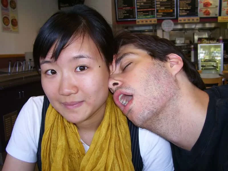 Micah, eyes closed and mouth open, pretending to fall asleep on Cecily’s shoulder while she smiles at the camera.